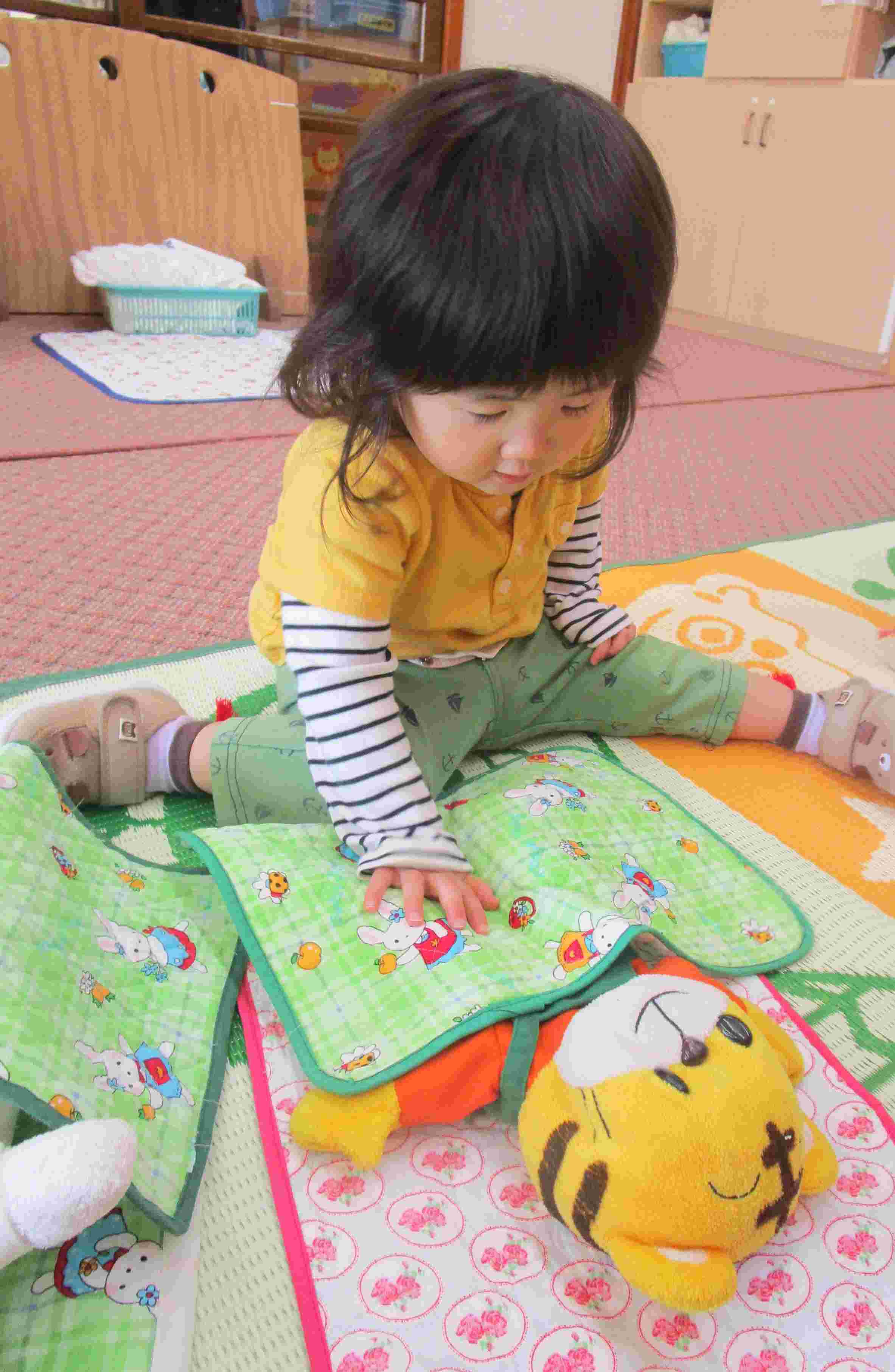 男の子が人形を布団に寝かしつけている